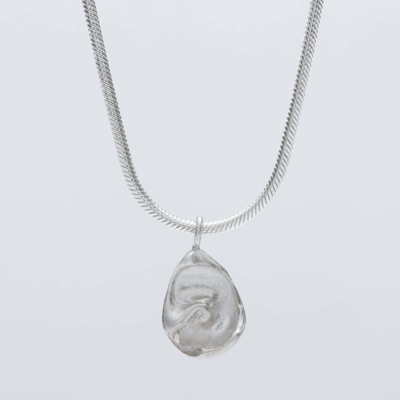 Handmade recycled silver fossil pendant hanging from a 2 mm silver snake chain