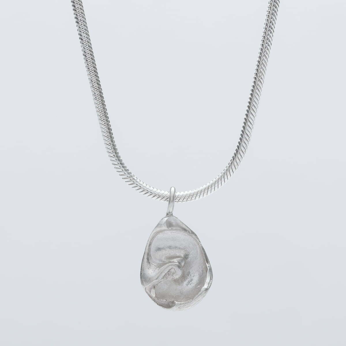 Handmade recycled silver fossil pendant hanging from a 2 mm silver snake chain